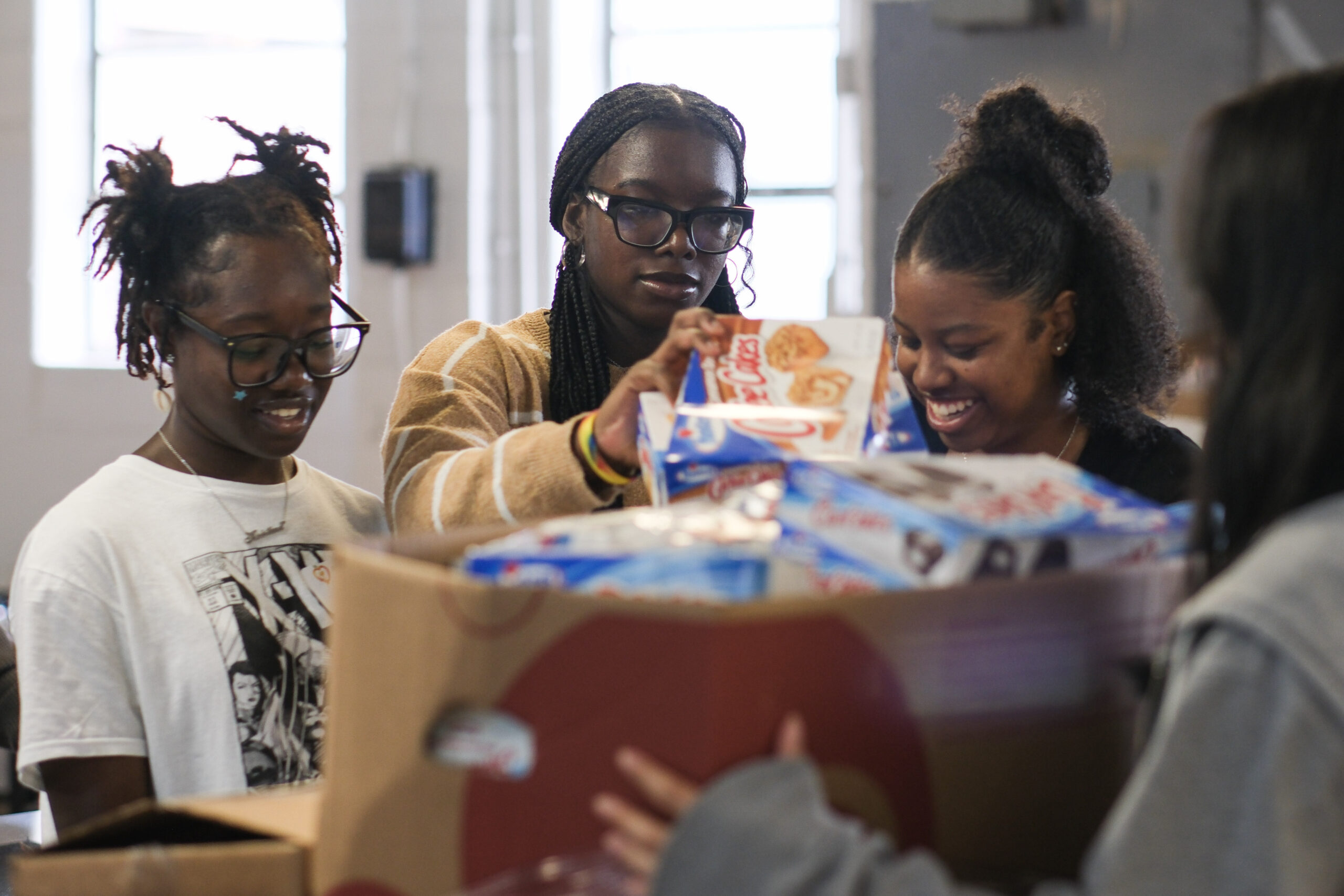 Student volunteers from Key School, from left, Kristina Ajayi, 16, Chloe McCarthy, 16, and Tayla Roan, 17, prepare food distributions at The Anne Arundel County Food Bank this week. Photo. (Tommy Tucker/Capital News Service)