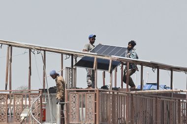 Technicians install solar panel plates