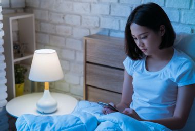 Woman in bed using a smartphone